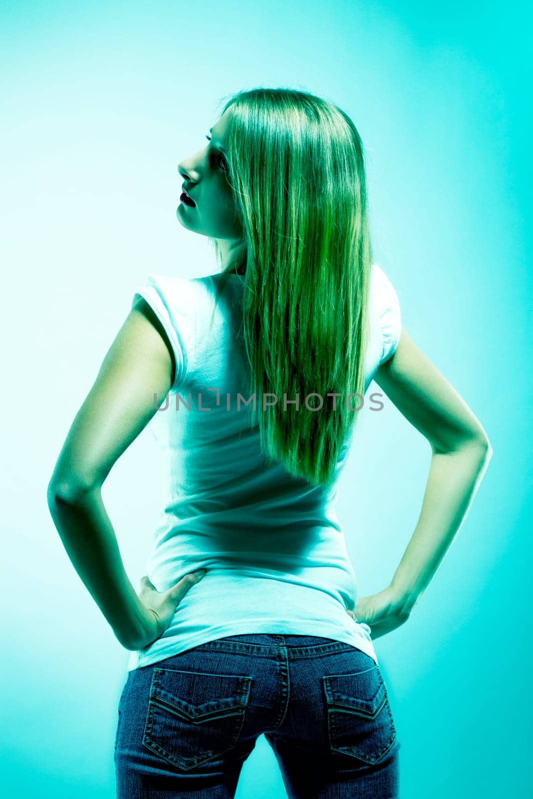 Young woman in jeans from behind in green light