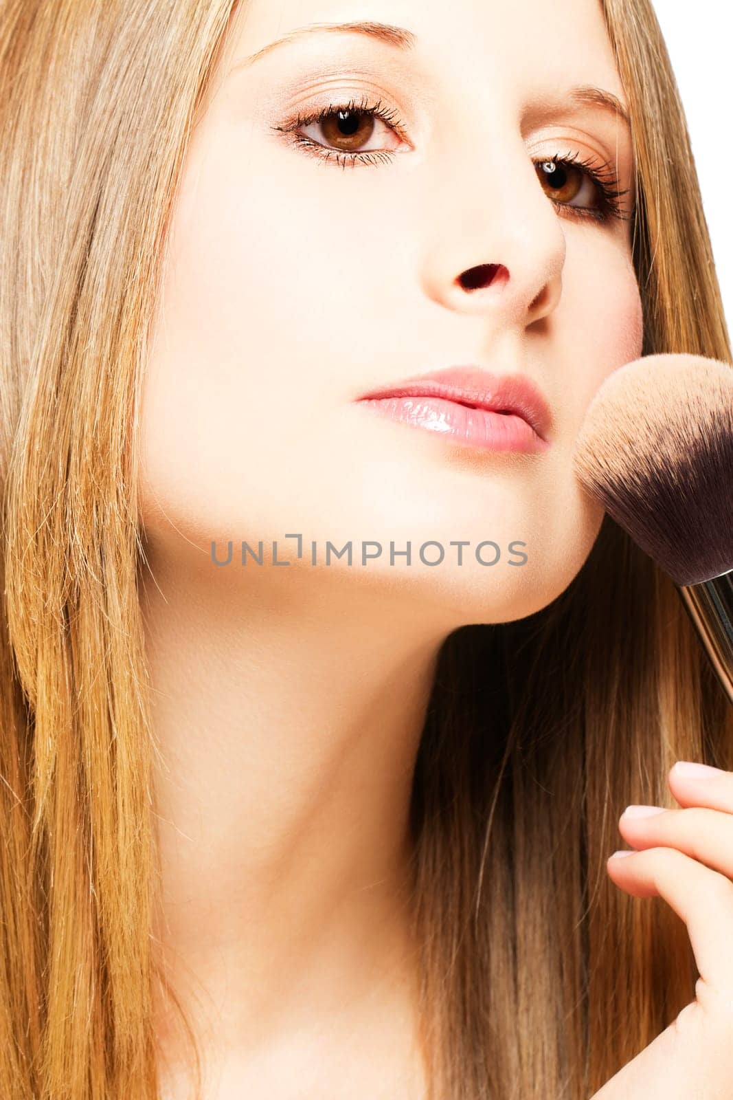 Young woman with brush applying makeup on white background