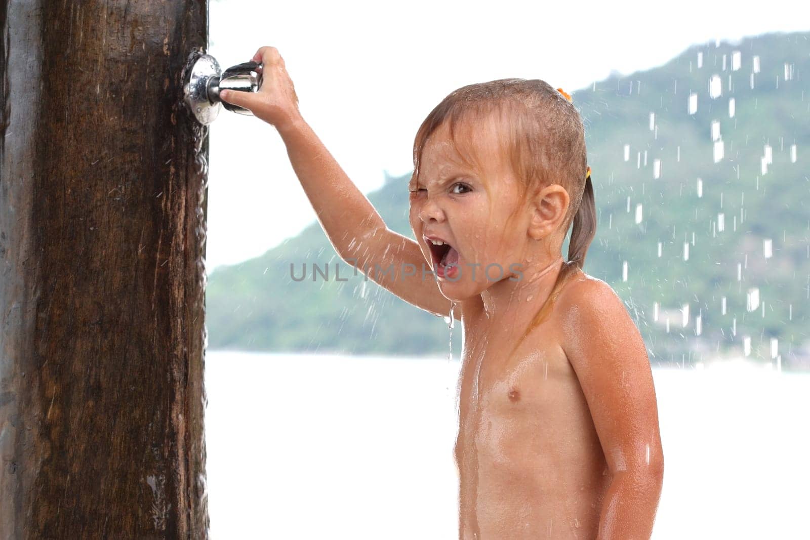 little girl in the sea under a shower valve closes