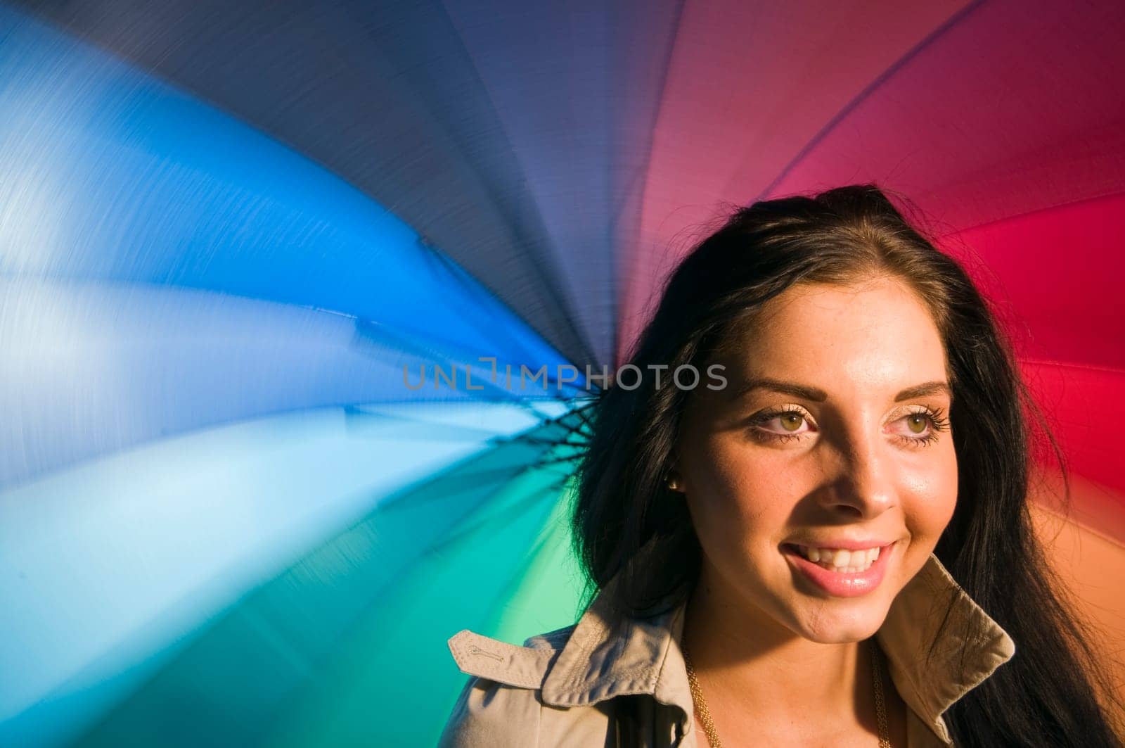 Head and shoulders portrait of a young black-haired woman with colorful umbrella as background