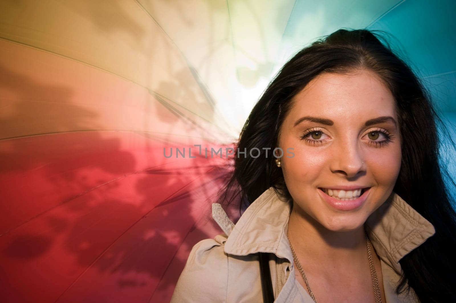 Head and shoulders portrait of a young black-haired woman with colorful umbrella as background