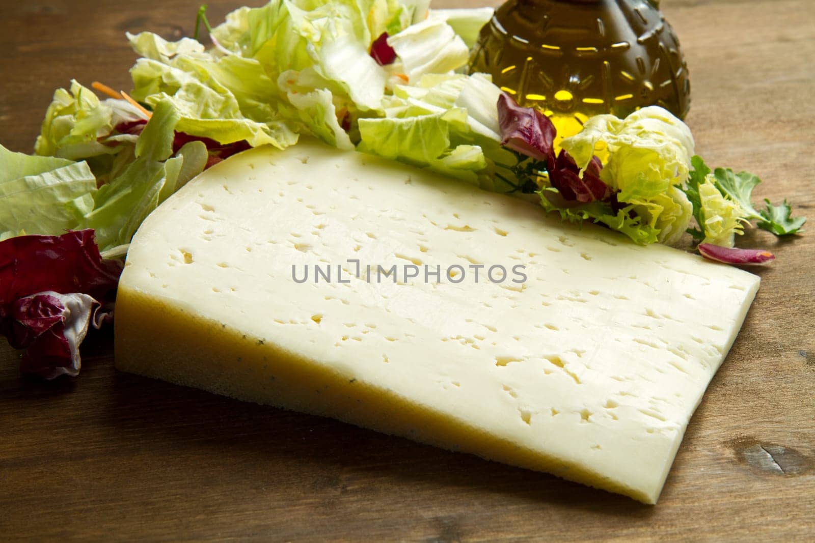 Asiago cheese with fresh salad on wooden table