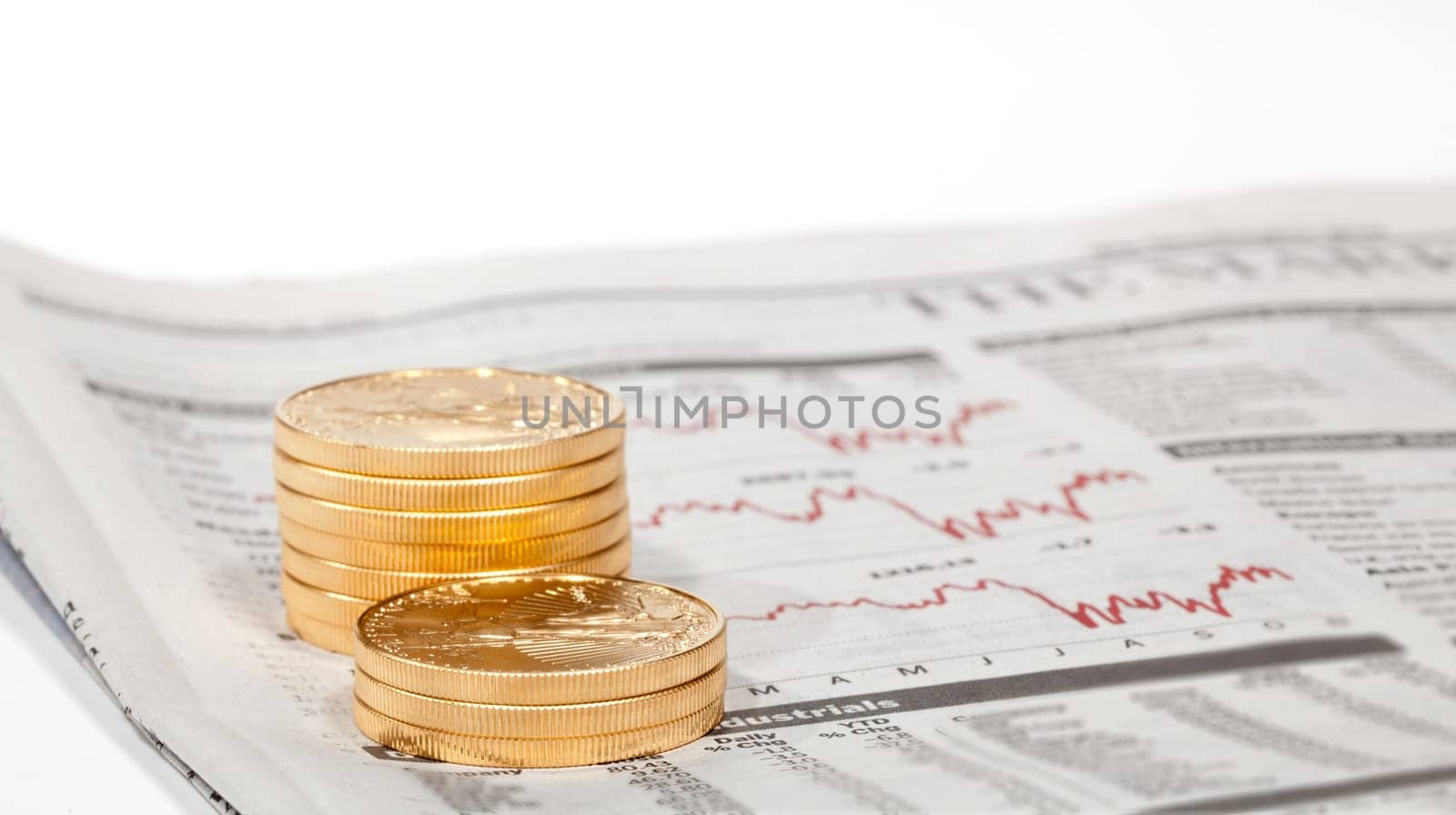 Gold Eagle one ounce coins stacked into columns on business pages of newspaper with graphs