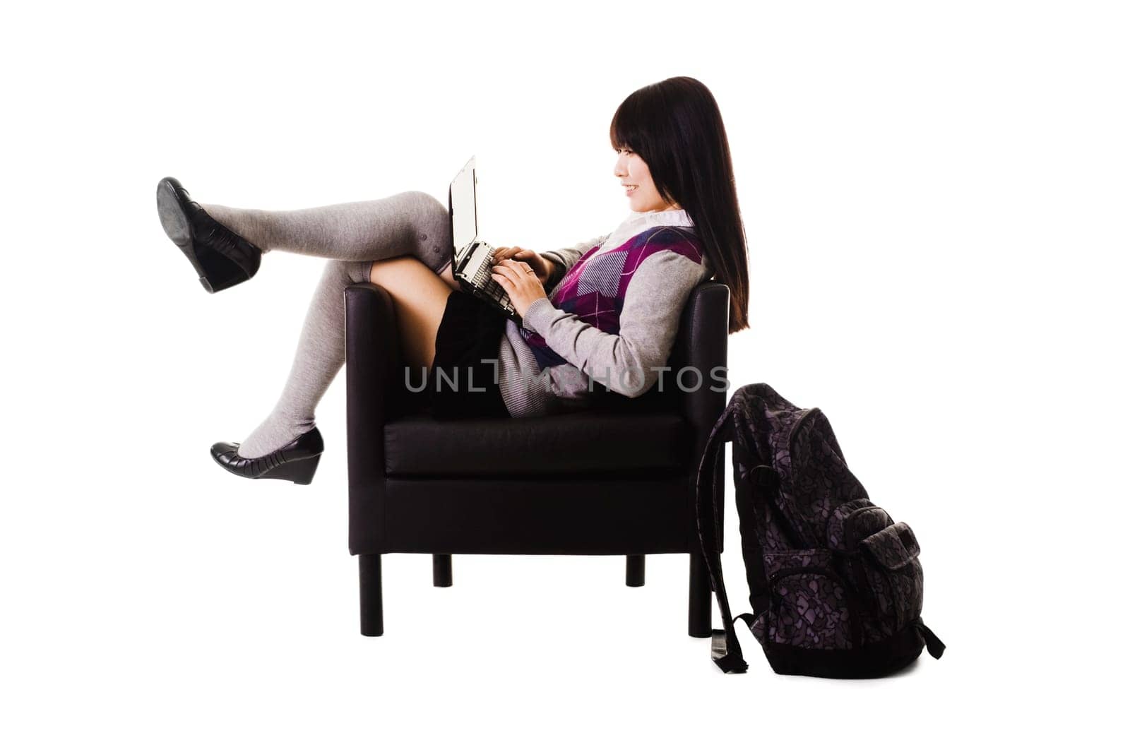 Chinese student working on a laptop while sitting in a leather chair.