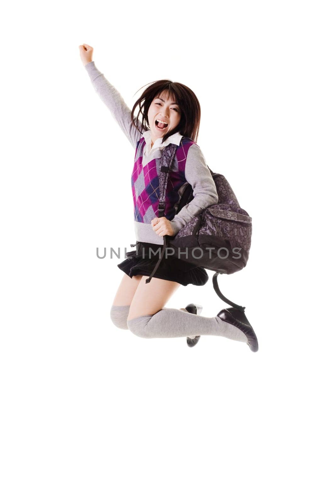 Female Chinese student with a backpack on a white background jumping in the air.
