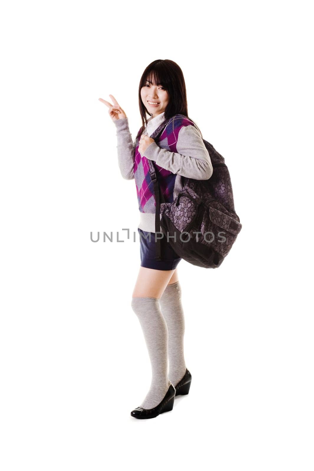 Female Chinese student with a backpack on a white background showing the peace sign.