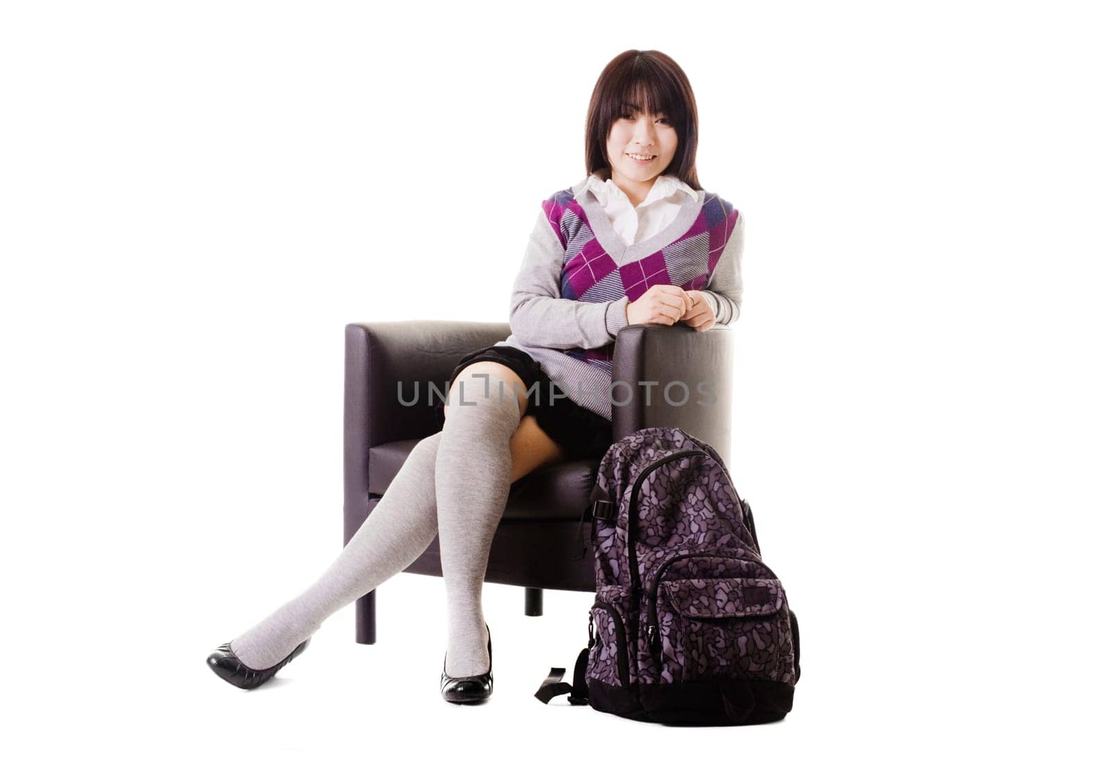 Portrait of a stylish Chinese school girl sitting in a leather chair.