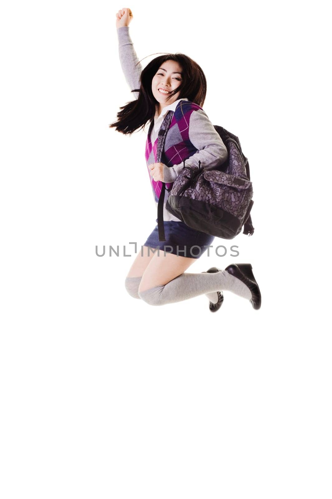Female Chinese student with a backpack on a white background jumping into the air.