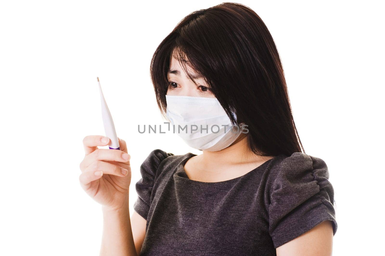 Closeup of a sick Chinese woman wearing a face mask and reading a digital thermometer.