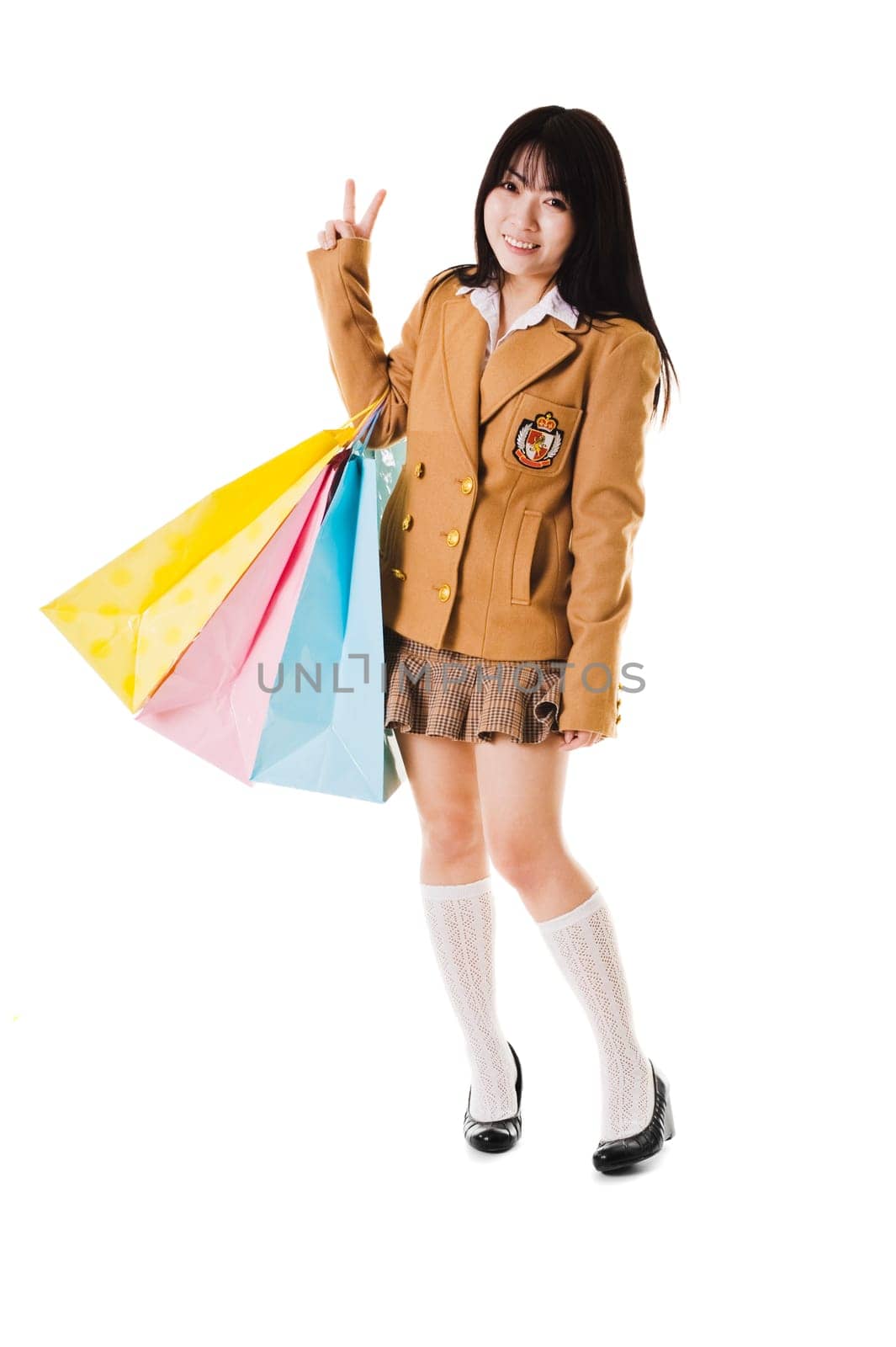Chinese school girl wearing a uniform holds shopping bags while showing a peace sign.