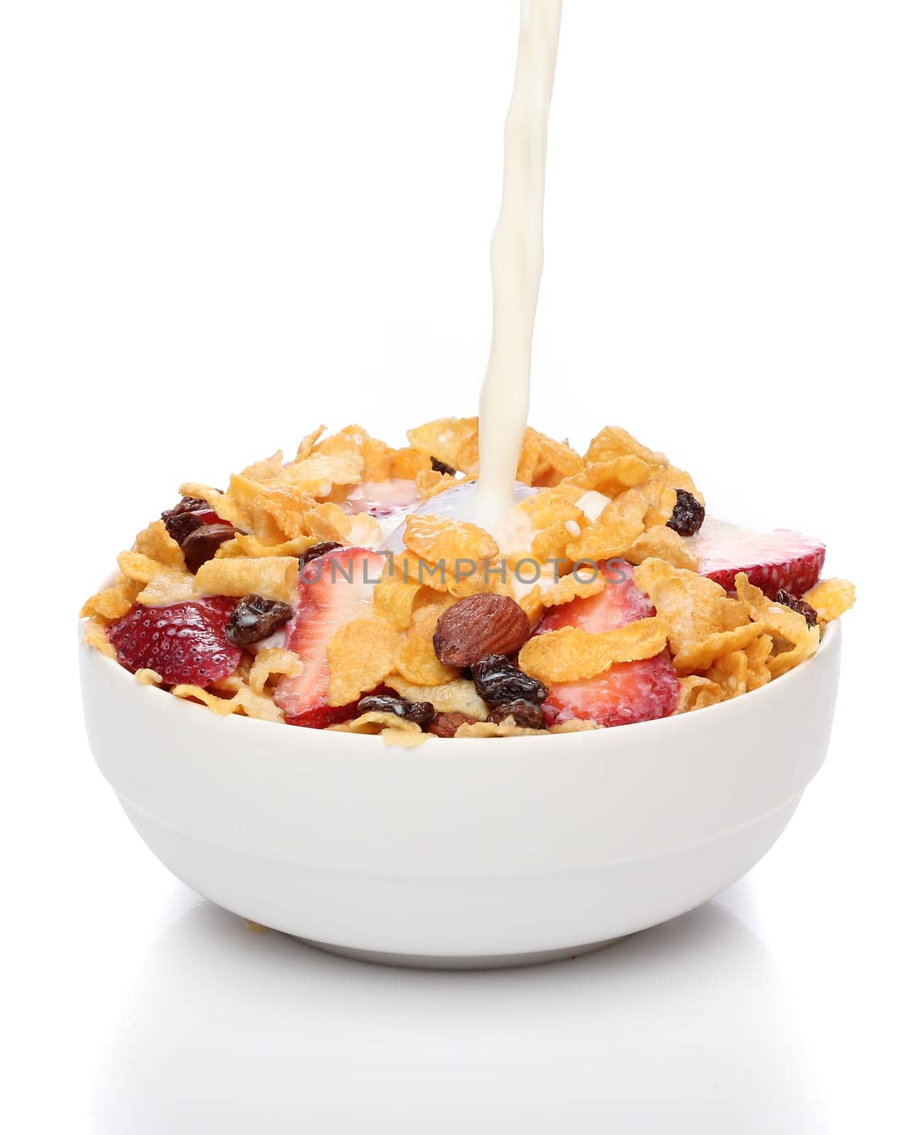 Pouring milk into a bowl of cornflakes and fruits