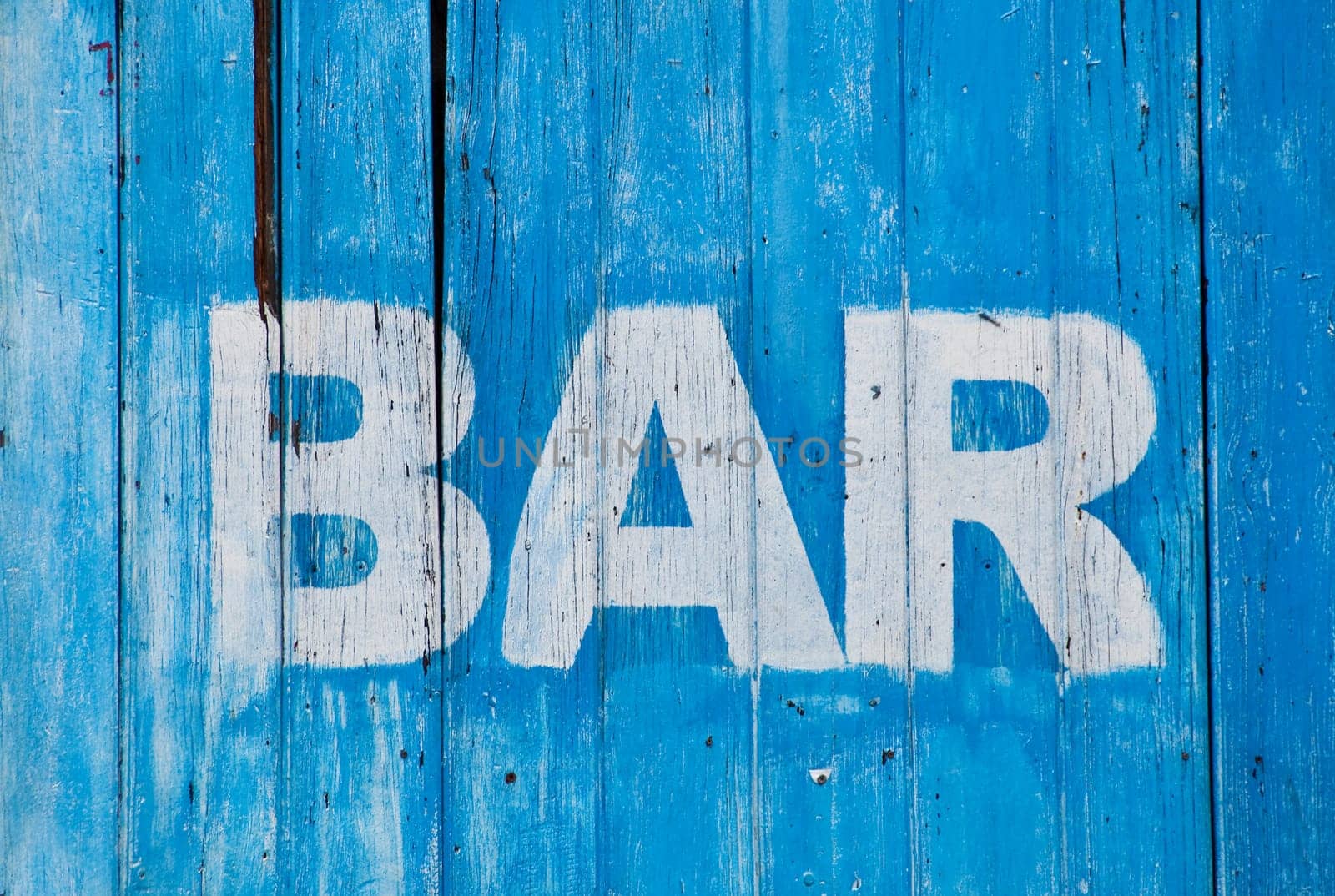 White bar sign painted on a dilapidated blue wooden wall