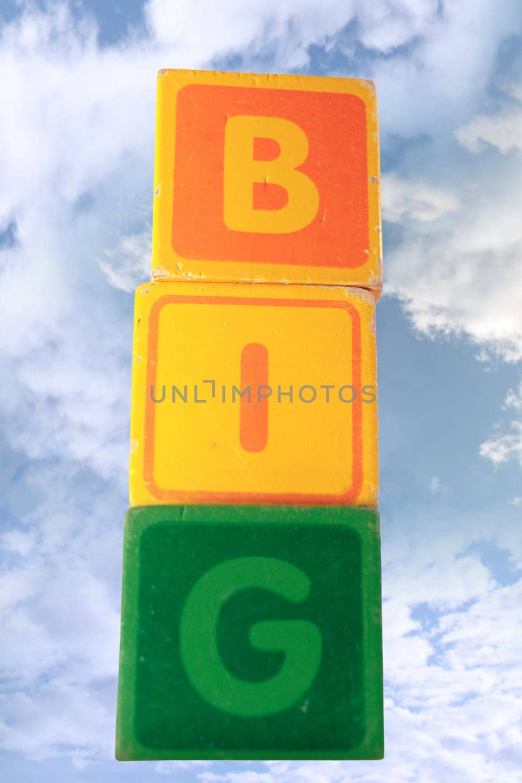 childrens toy letter building blocks against a cloudy background spelling big