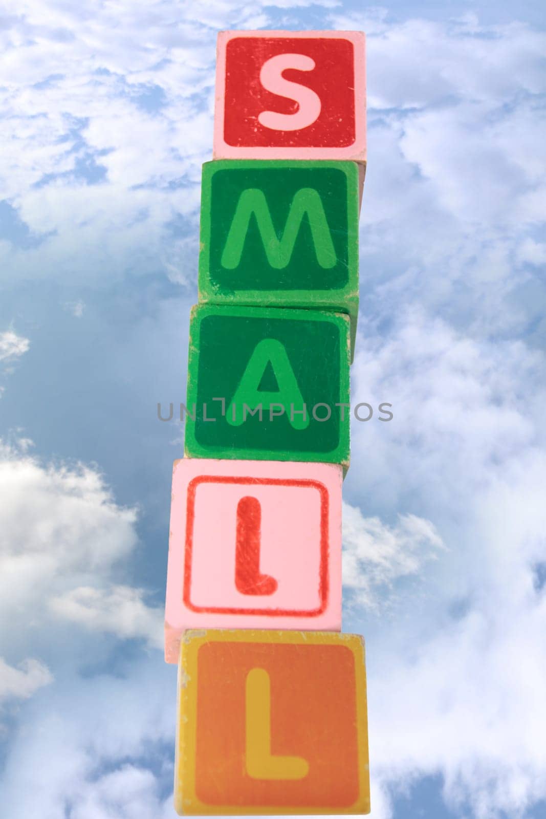 childrens toy letter building blocks against a cloudy background spelling small with clipping path