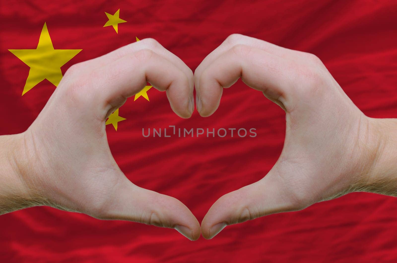 Gesture made by hands showing symbol of heart and love over china flag