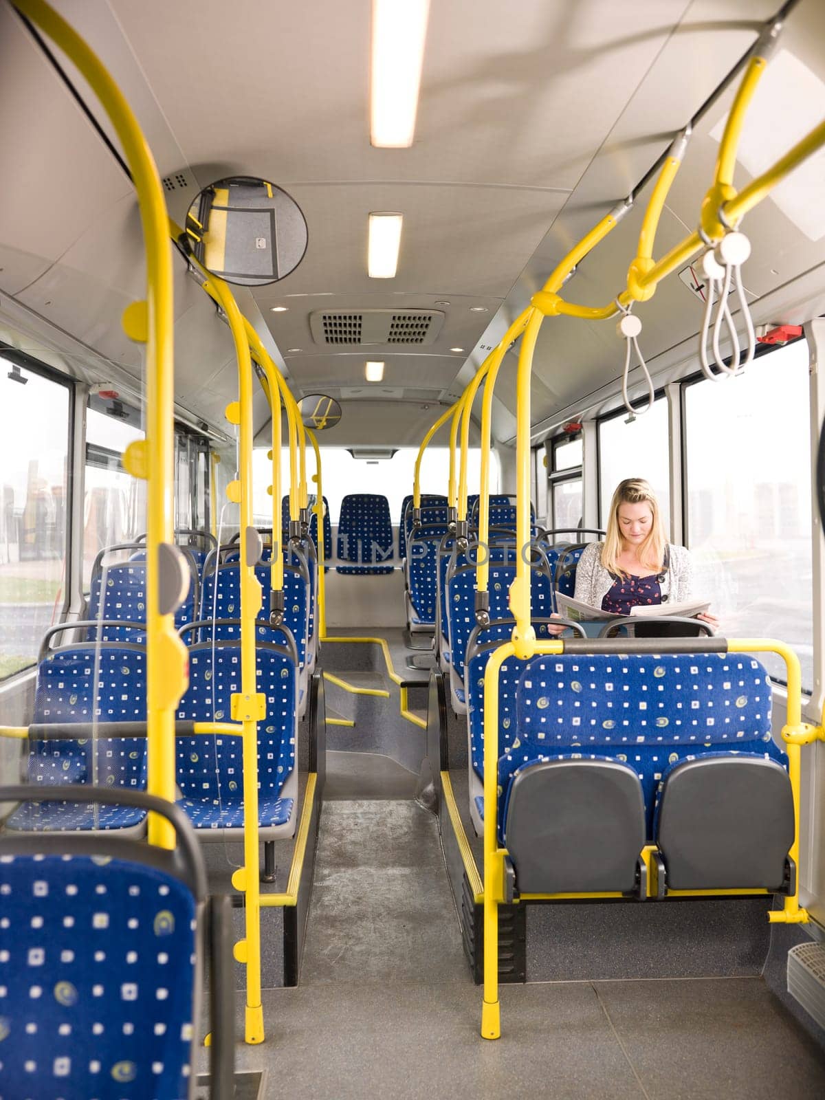 Lonely woman on the bus reading a newspaper