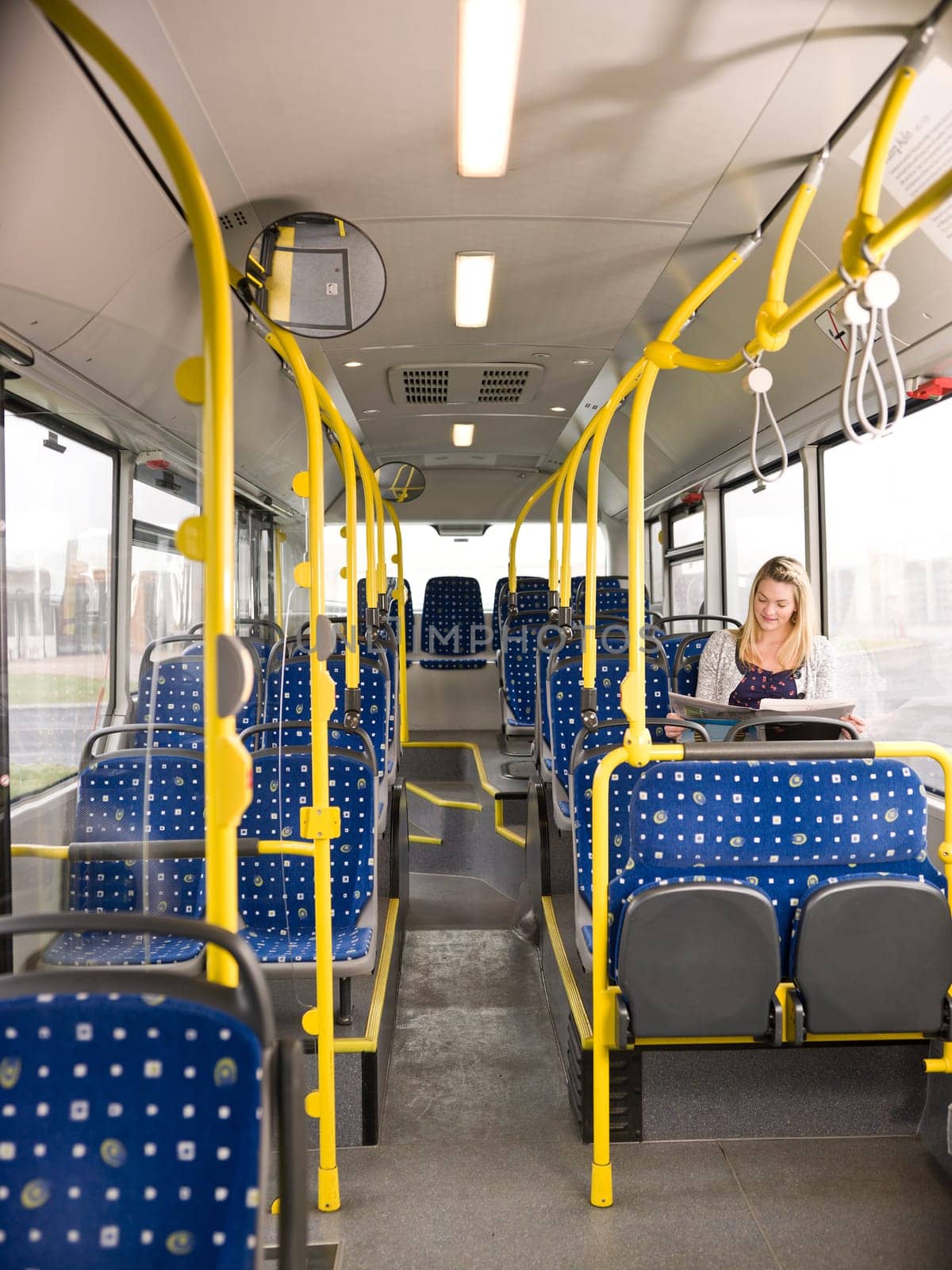 Lonely woman on the bus reading a newspaper