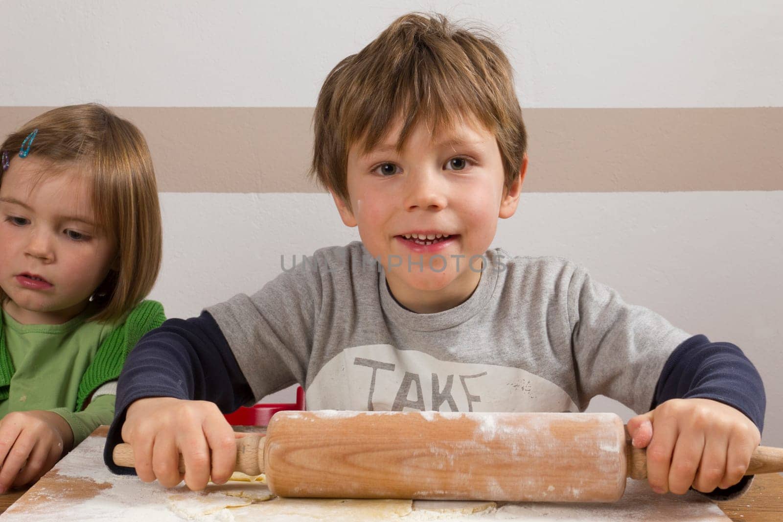 A boy flattens the dough with a rolling pin to make cookies