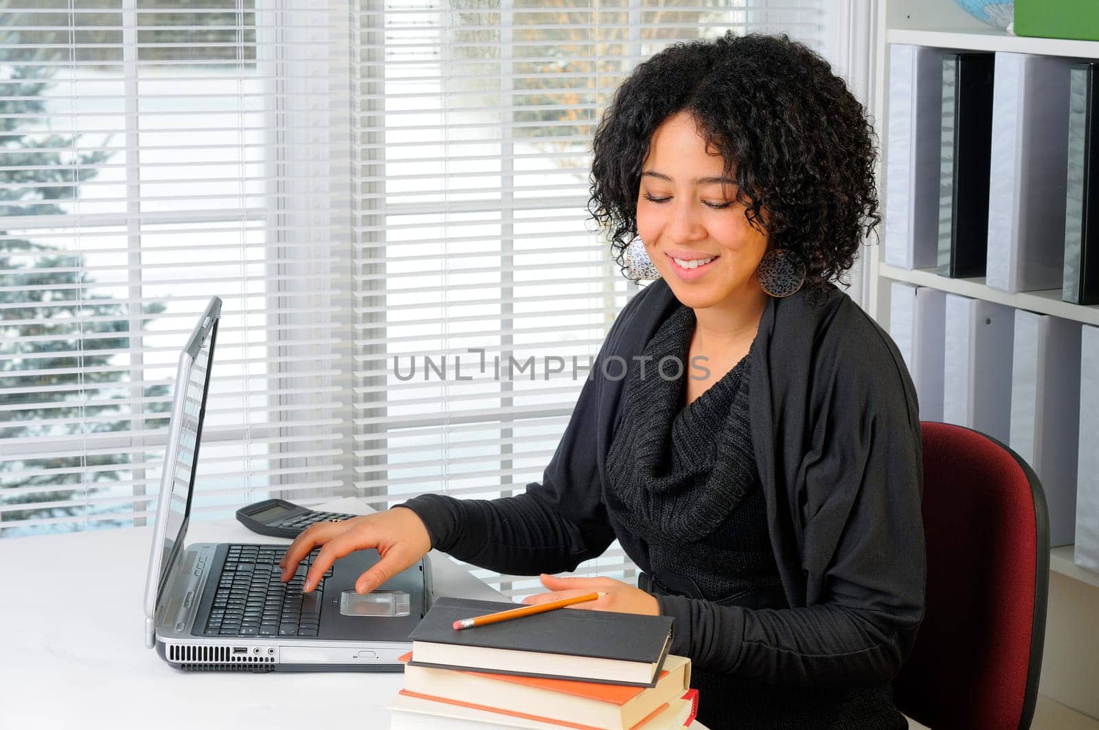Young Woman Sat At Her Desk Using A Laptop Computer In Class At School