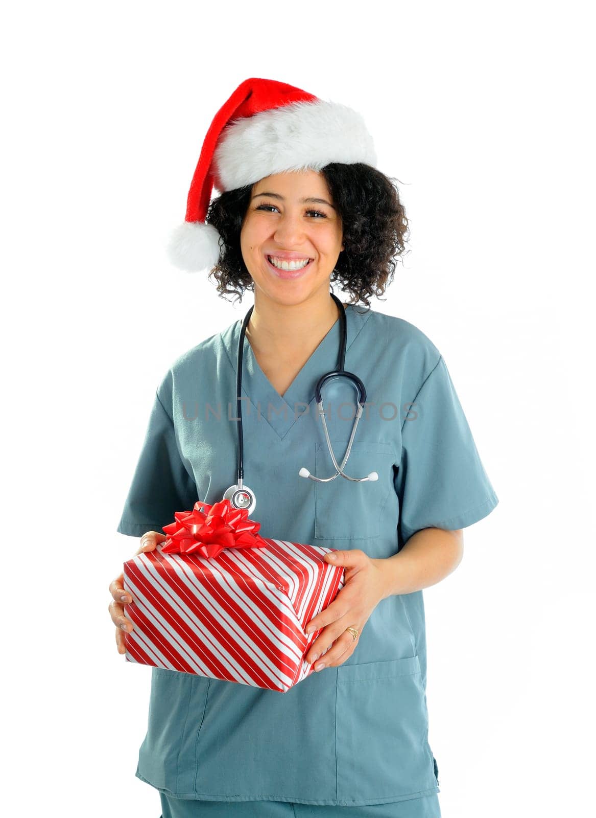 African American Female Nurse Wearing Hospital Scrubs And A Santa Hat Carrying A Christmas Gift