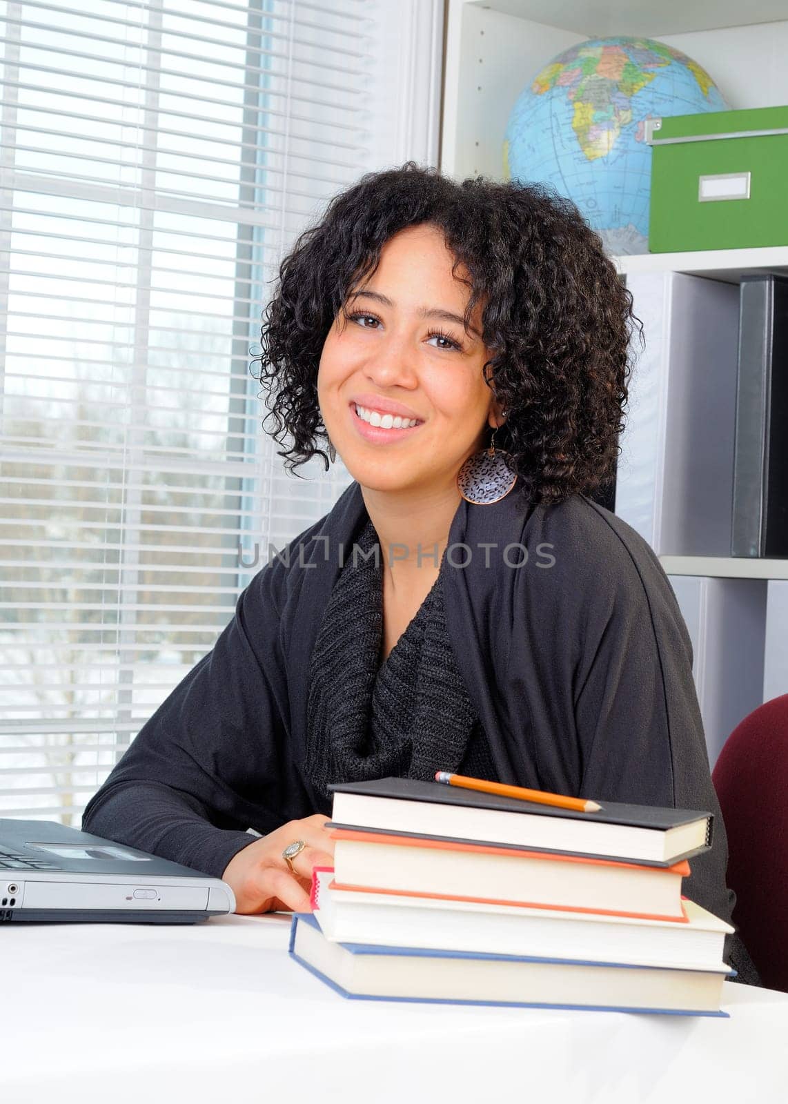 Pretty African American Female Student Sat At Her Desk With Laptop Computer And Globe, Concept For Education At The High School Or College Level.