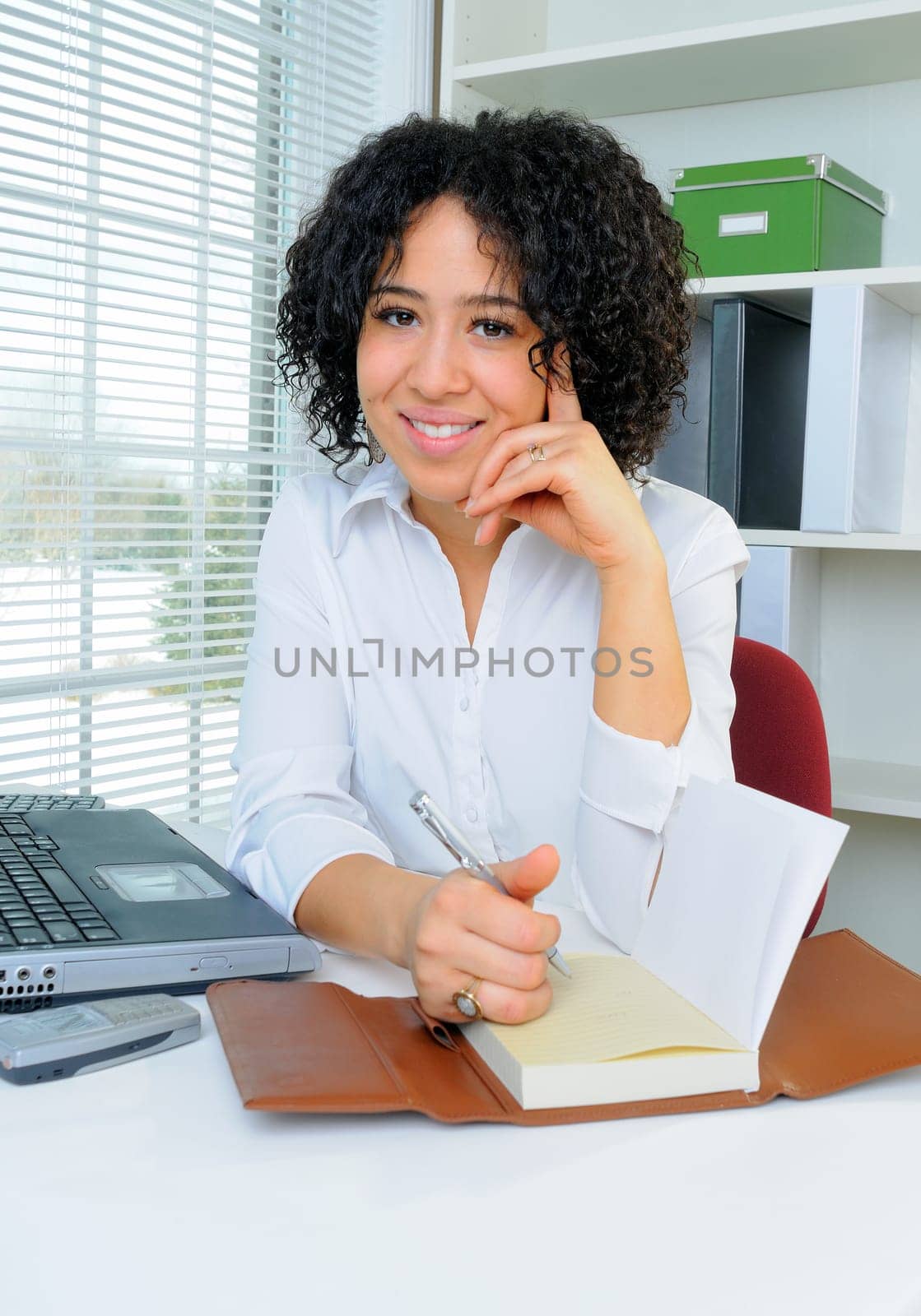 African American Business Woman Sat At Her Desk Writing Notes In Her Diary