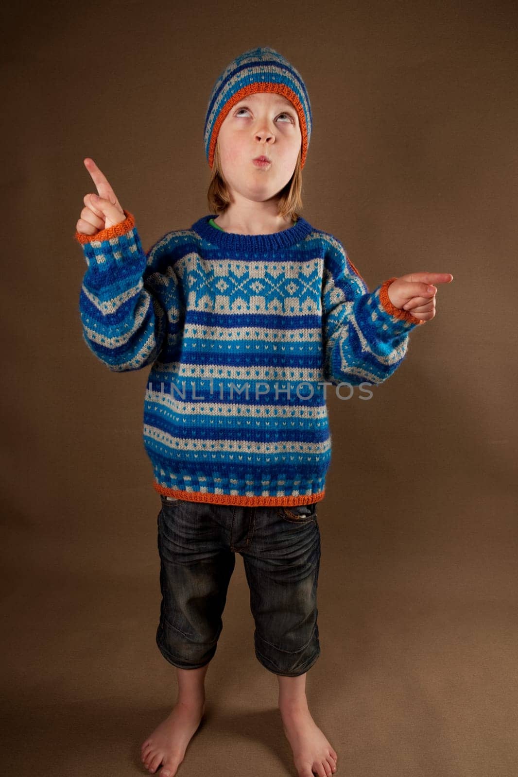 child in sweater or knit wear. cute blonde boy with long blond hair on retro brown background