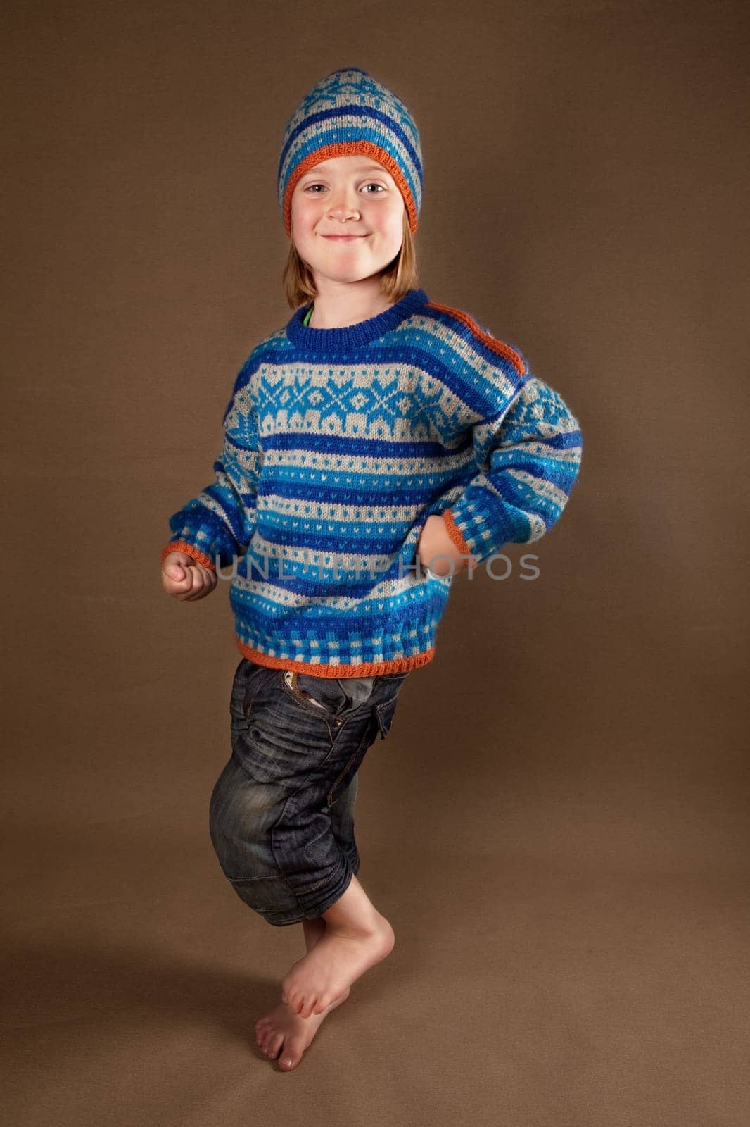 child in sweater or knit wear. cute blonde boy with long blond hair on retro brown background