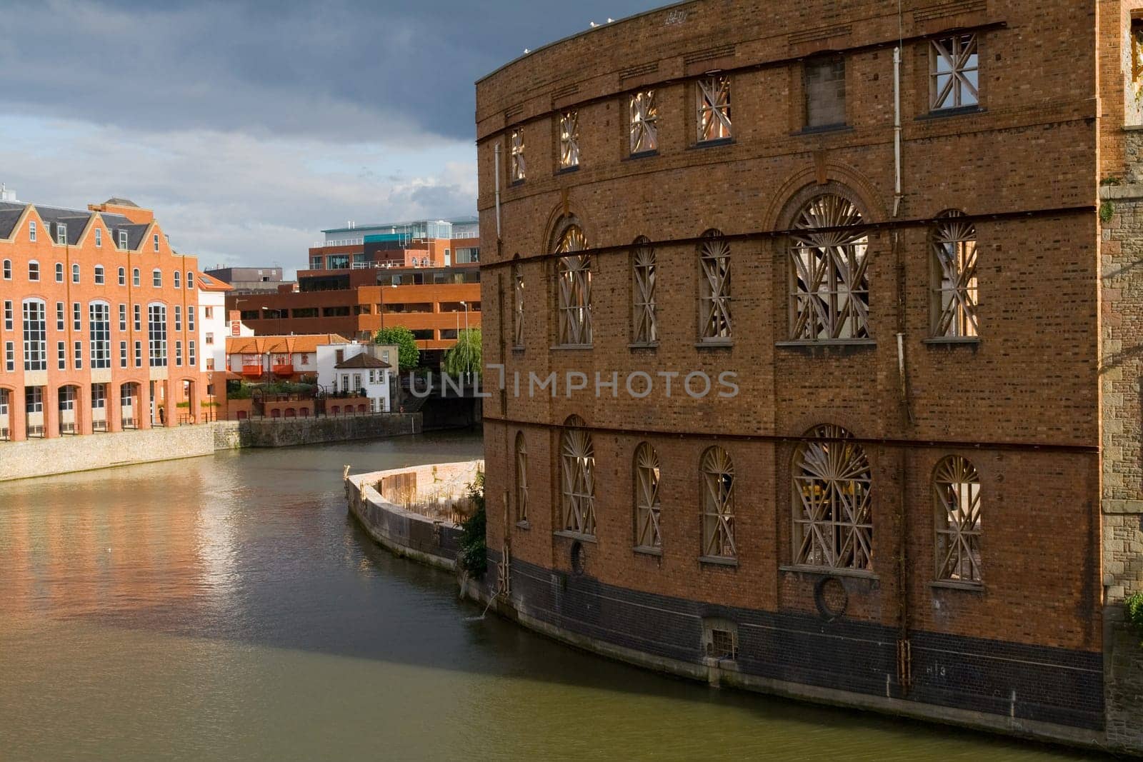 housing or development of flats by the river or canal in bristol in england. view of old building by water