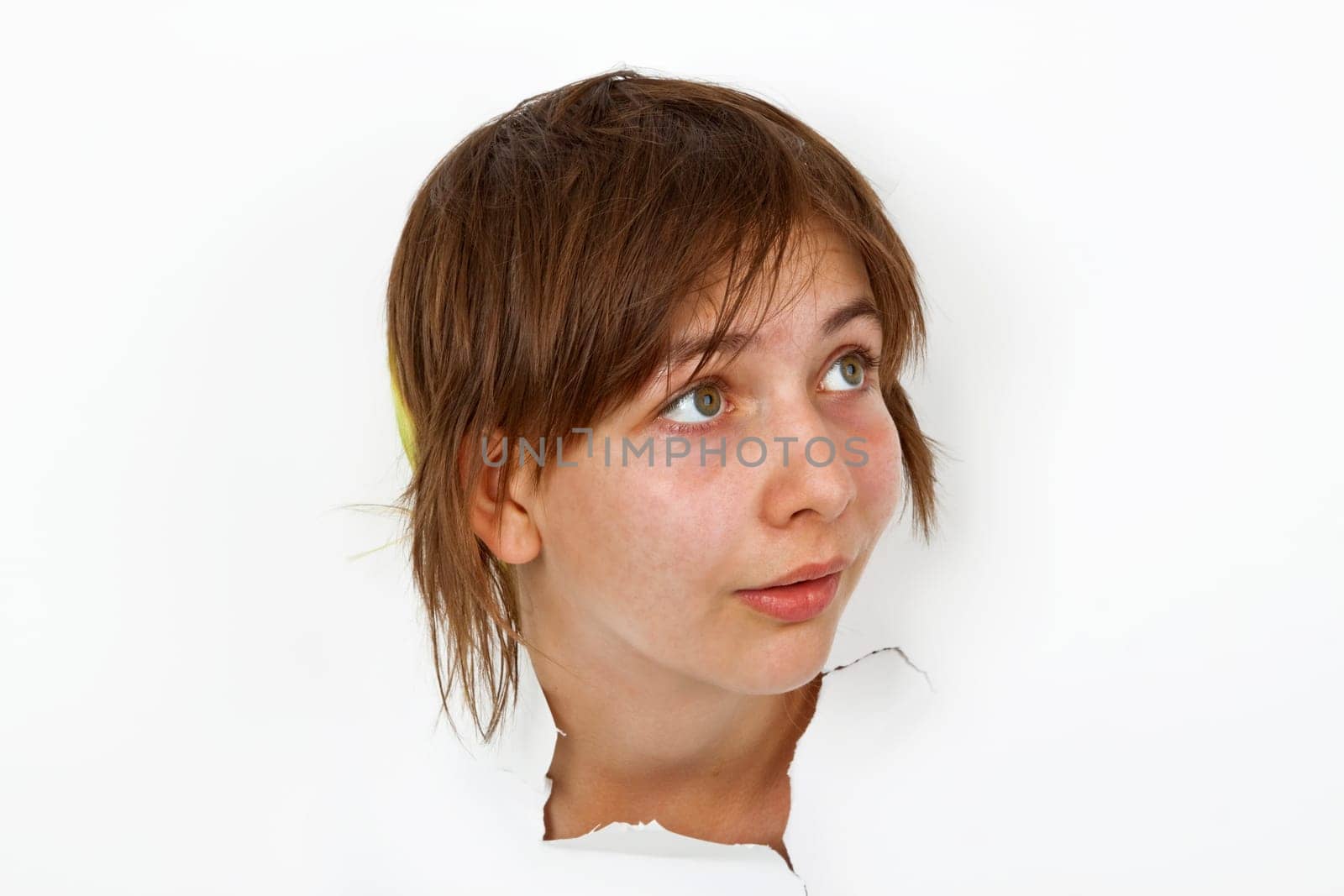 Young woman looking out of white paper