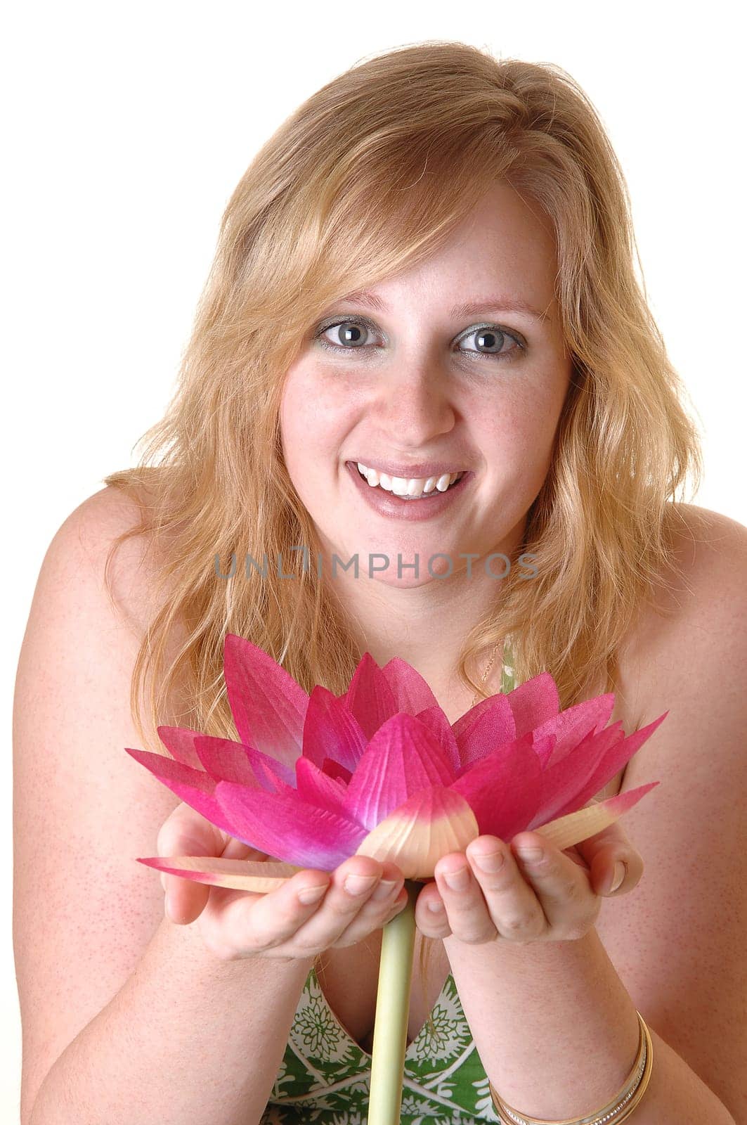 An gorgeous teenager girl in a green dress with a pink water lily in her hand standing in the studio with a pretty smile, for white background.