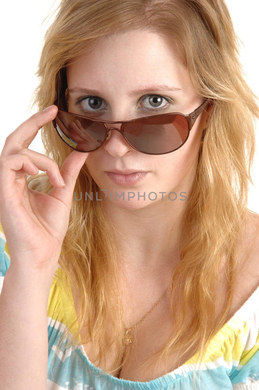 A lovely teenage girl in closeup holding her sunglasses and looking over the frame, with blond hair and necklace, over white background.