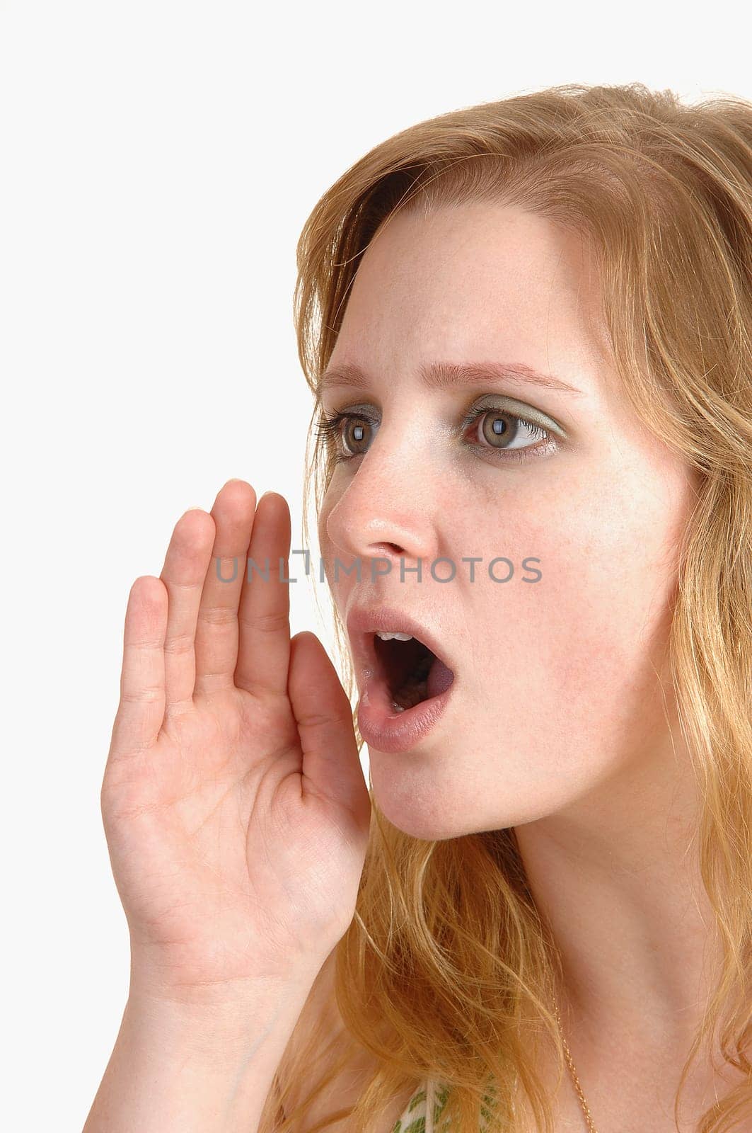 An serious teenage girl shouting a warning , with her mouth open and her hand at her face and with blond hair, over white background.