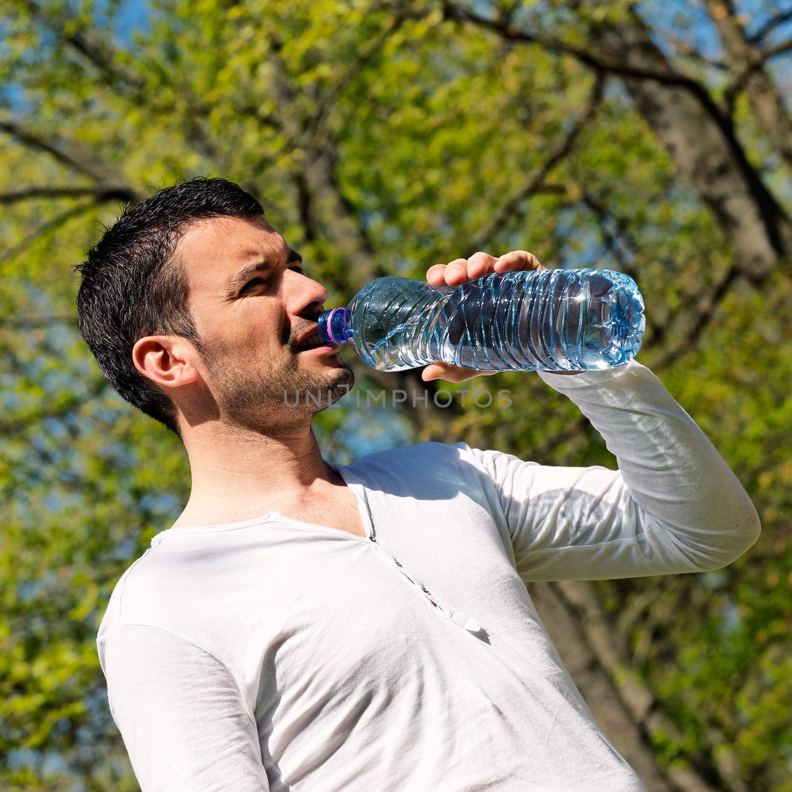 man drinking water after sport in a park