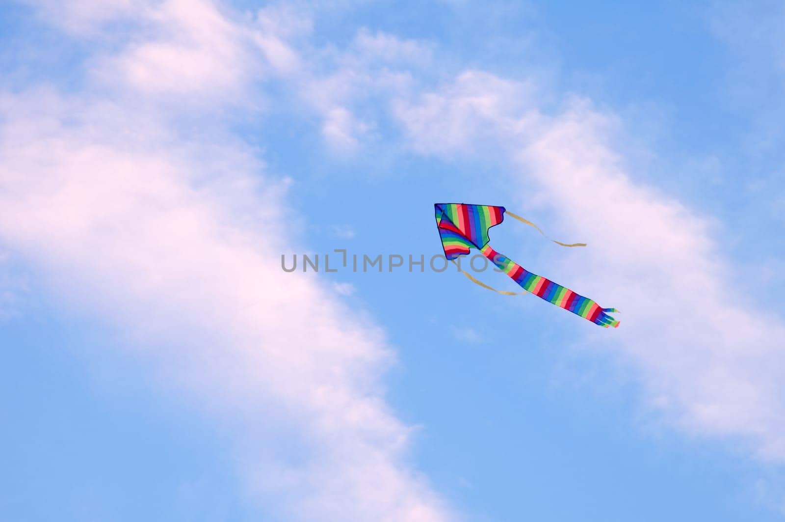 multicolored striped kite flying in the blue sky