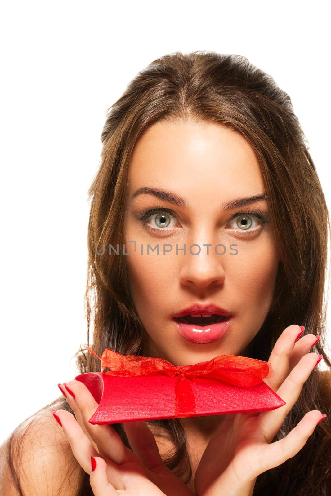 Beautiful woman with wide open eyes holding gift on white background