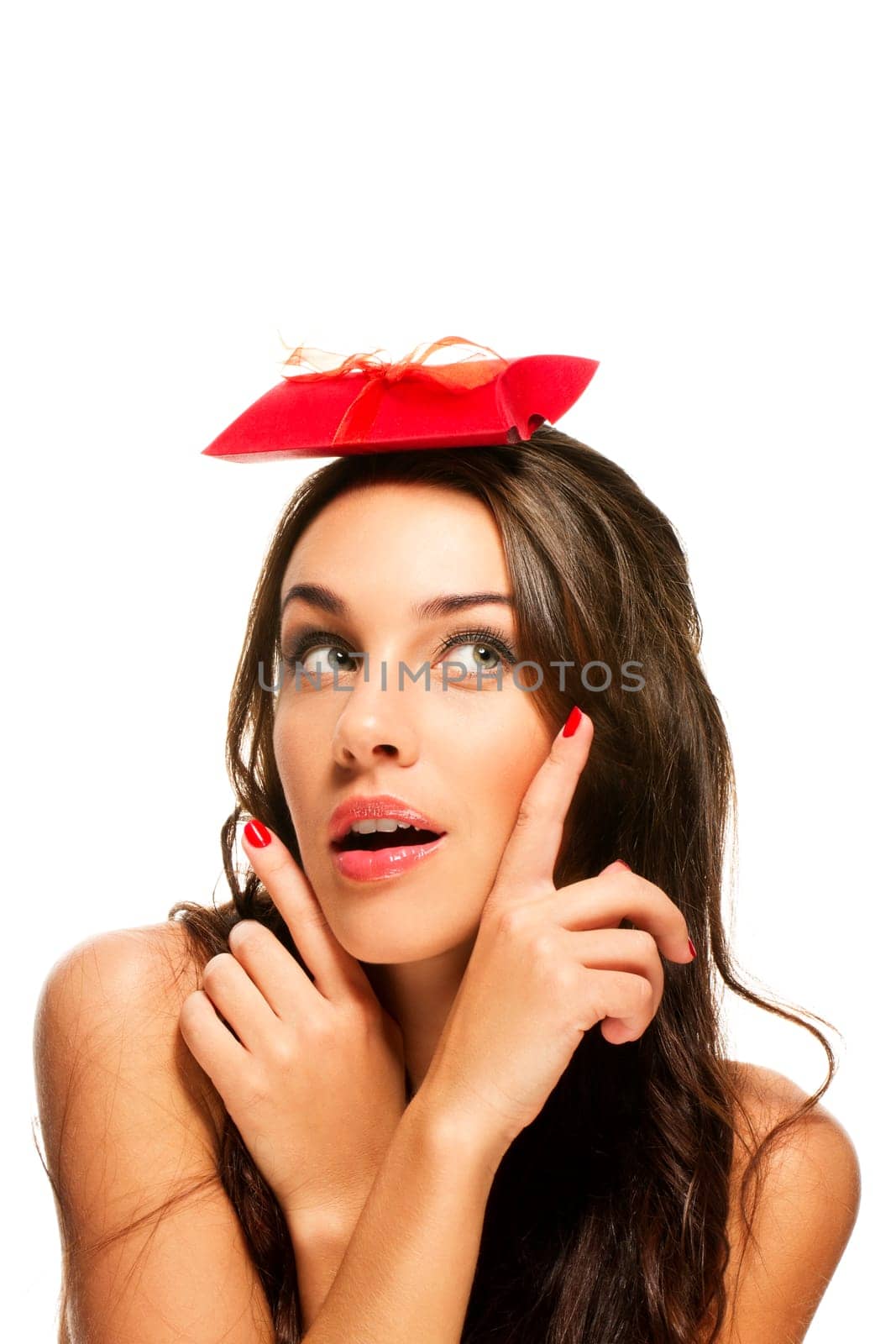 Brunette woman pointing with fingers at the gift on her head on white background