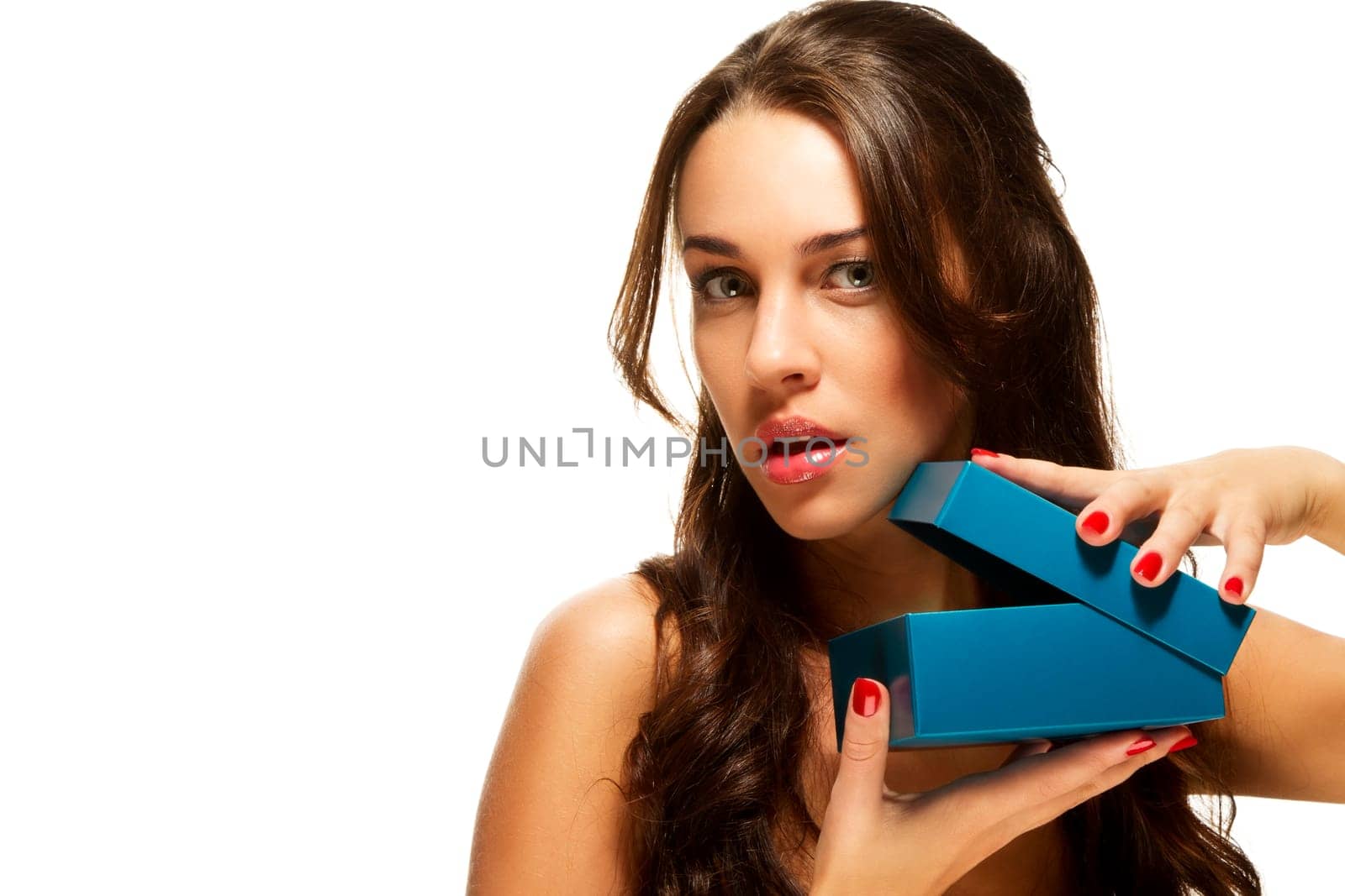 Beautiful brunette woman opening gift on white background