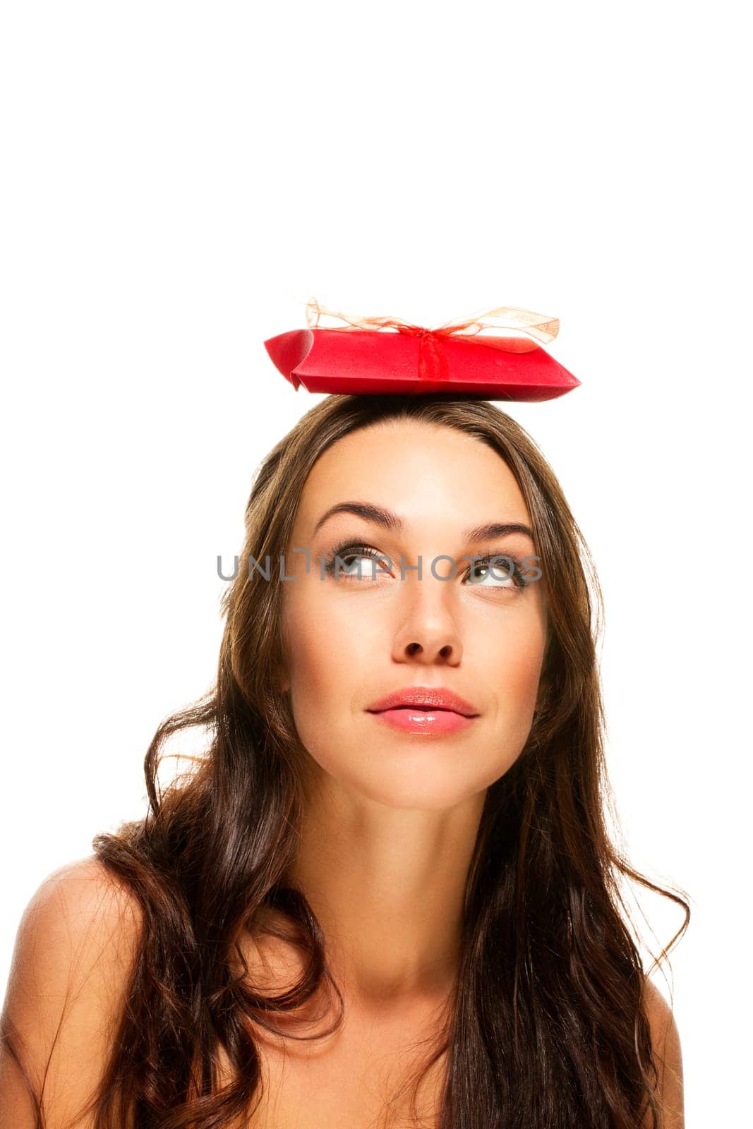 Beautiful woman looking up at the gift on her head on white background