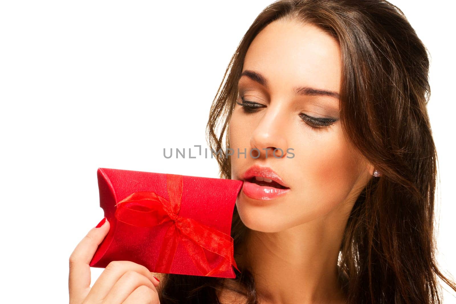 Beautiful woman holding red gift close to her face on white background