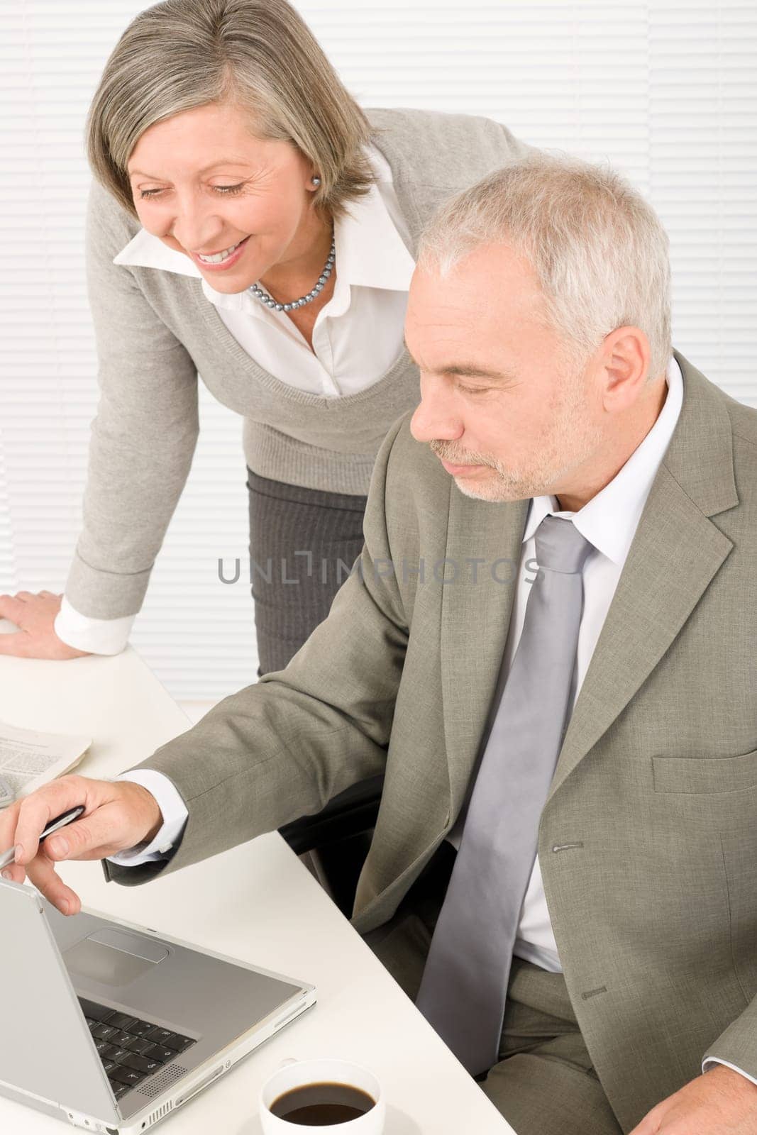 Professional businesspeople behind office table with laptop