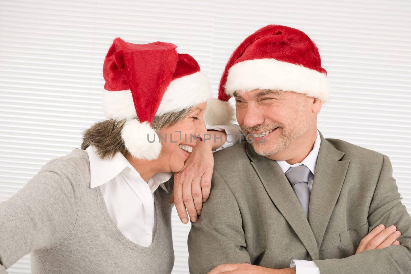 Laughing senior businesspeople having fun with Xmas Santa hat