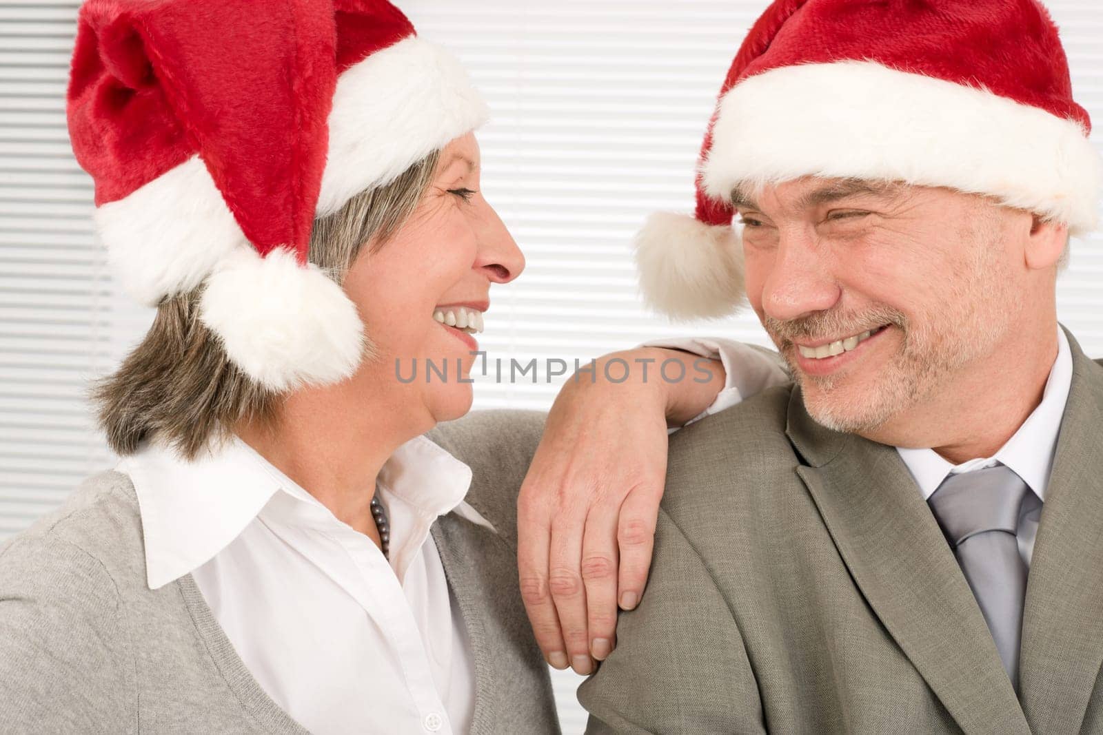 Laughing senior businesspeople having fun with Xmas Santa hat