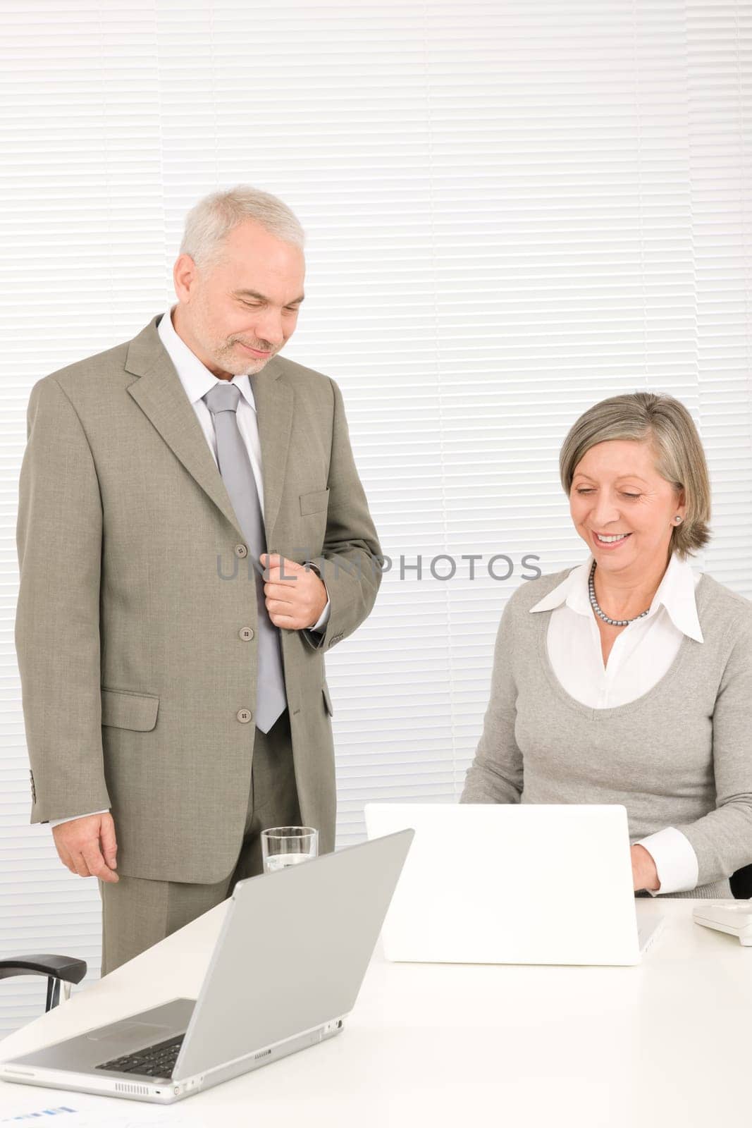 Professional senior businessman looking at computer with woman colleague