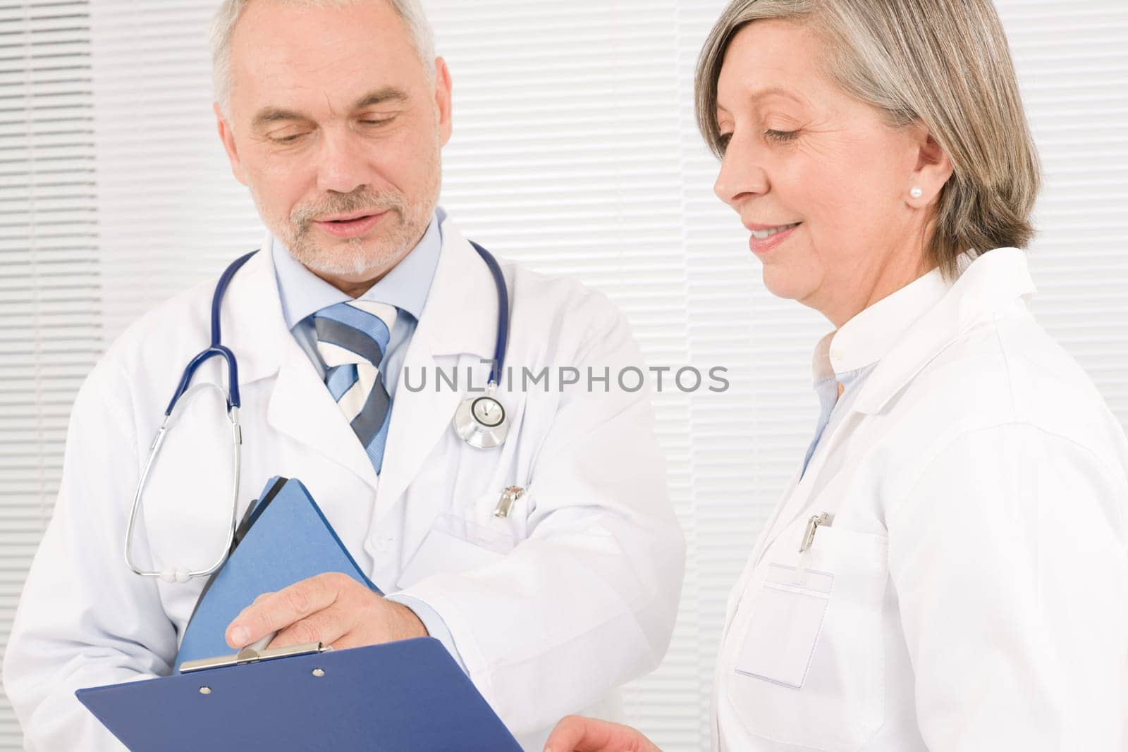 Medical doctor team senior woman and mature man holding folders