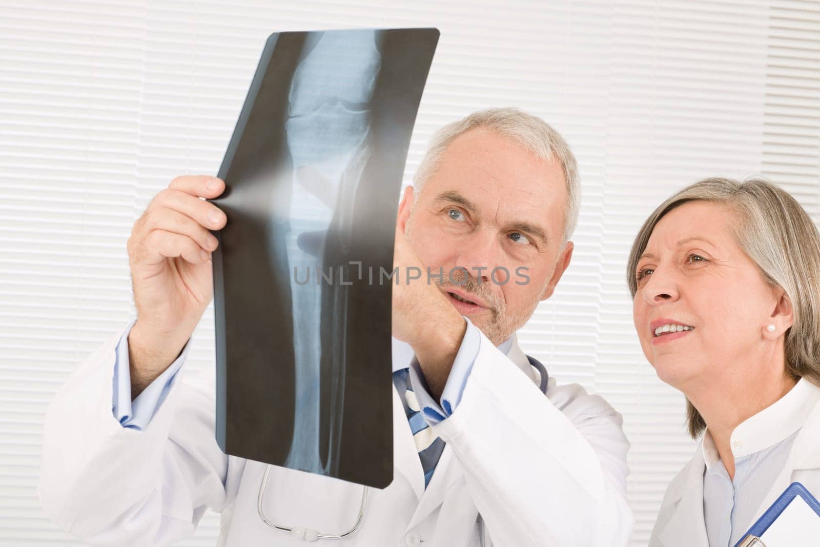 Medical doctor team senior man with female colleague look x-ray