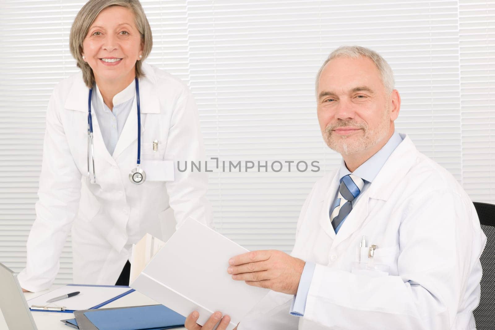 Medical senior doctor male reading book with professional female colleague