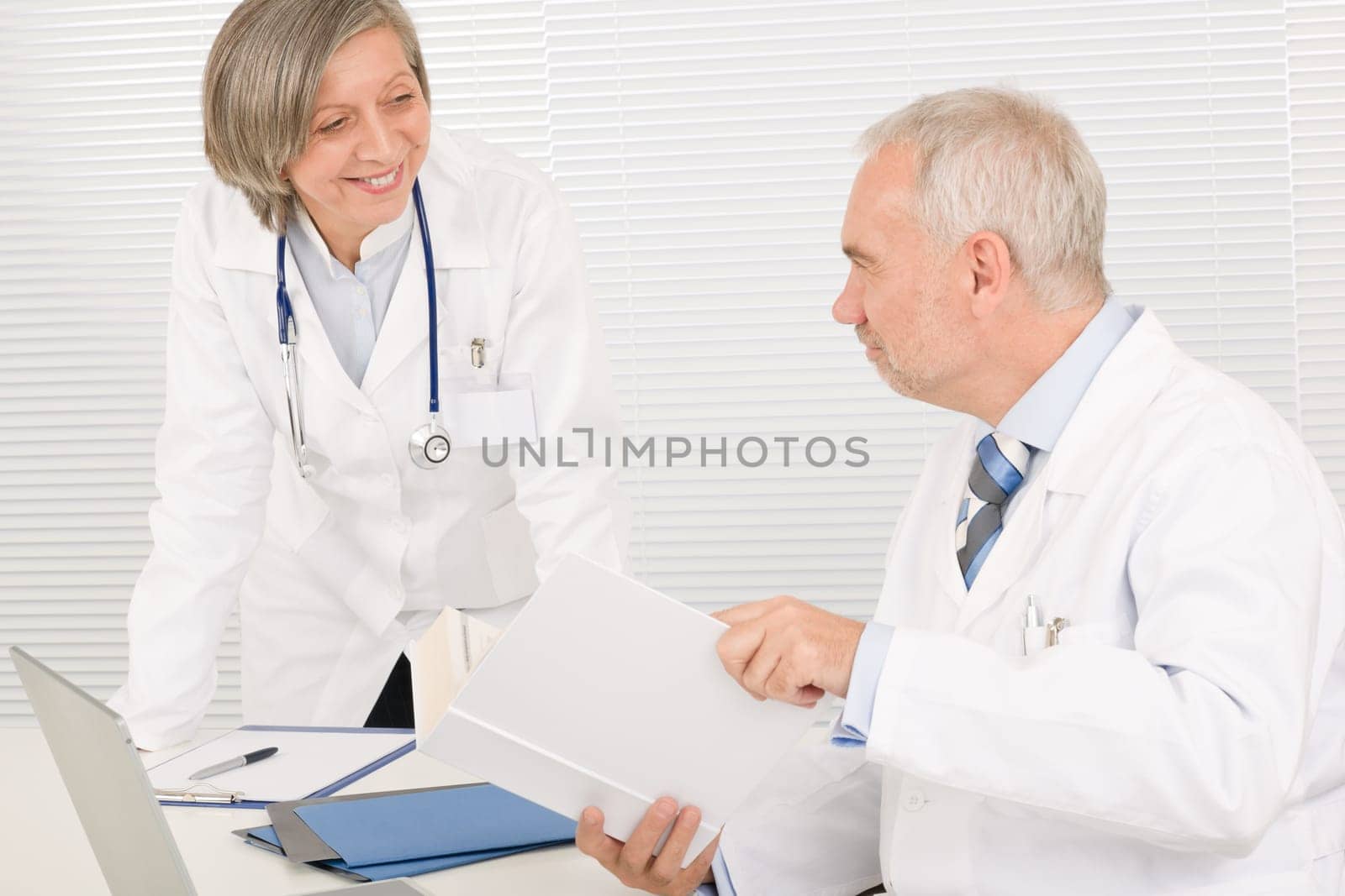 Medical senior doctor male reading book with professional female colleague