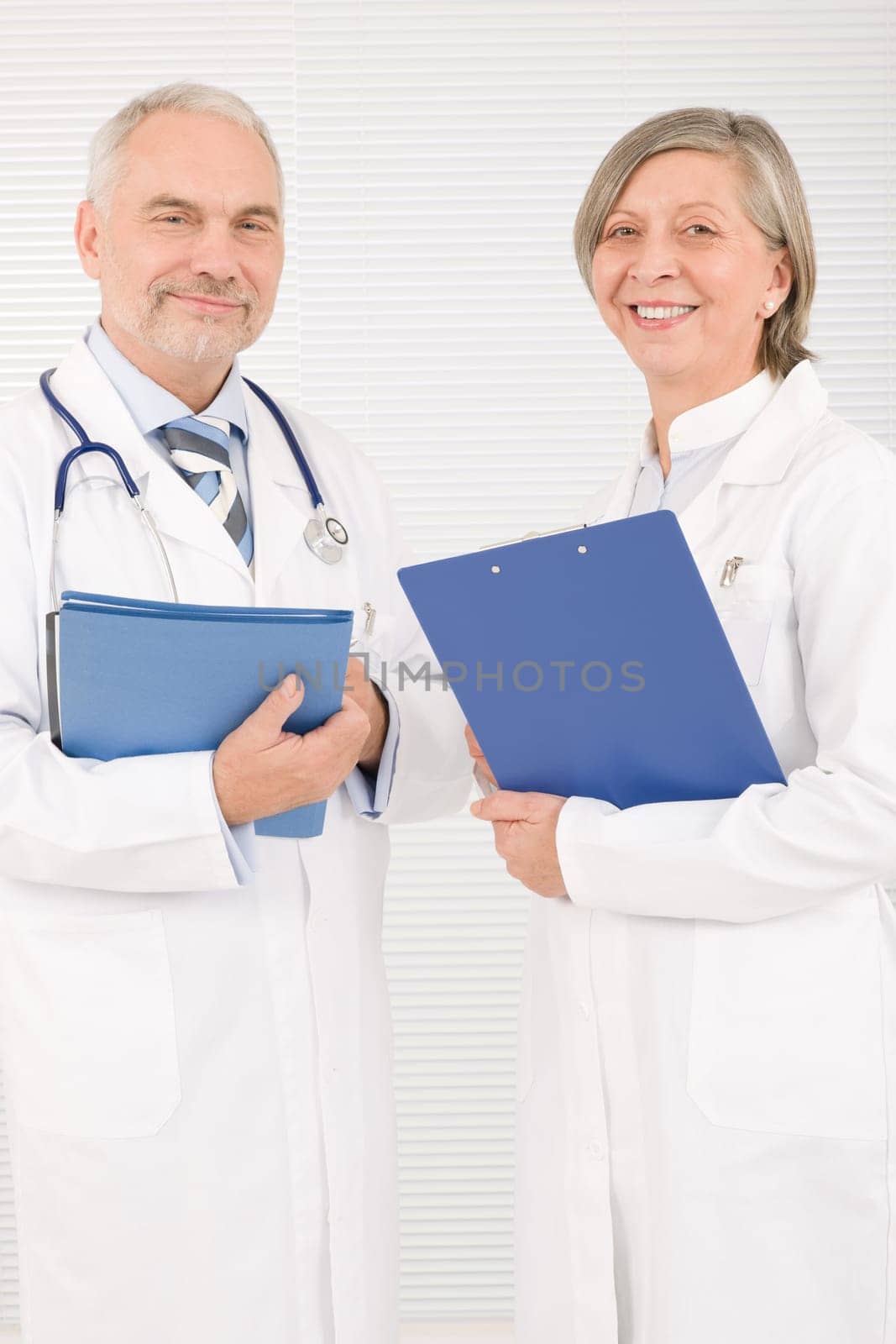 Medical doctor team senior woman and mature man holding folders