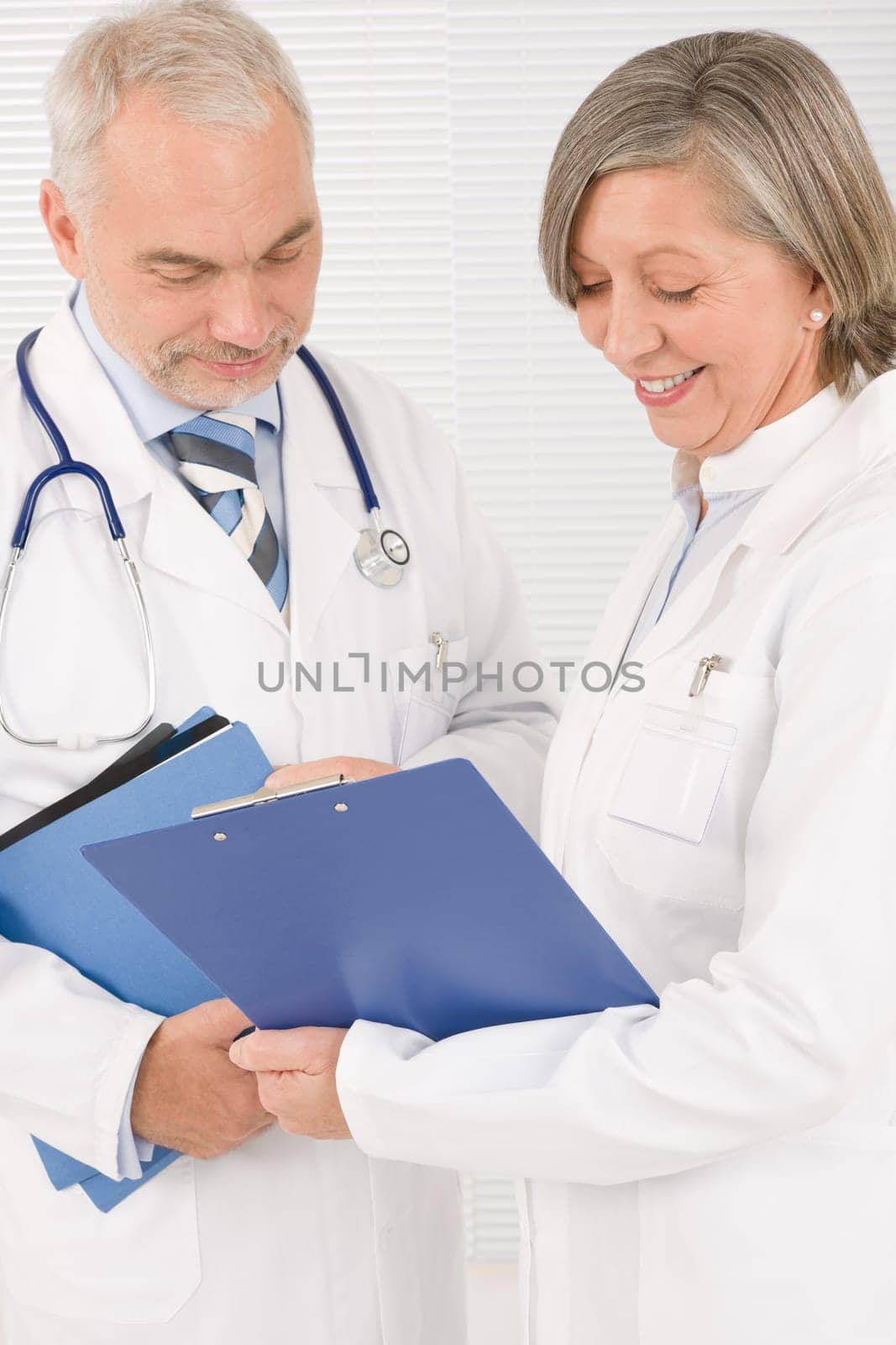 Medical doctor team senior woman and mature man holding folders
